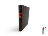 an old book sitting on top of a white surface with a red cover