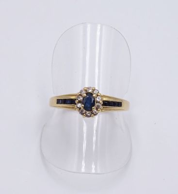 gros plan d'une bague en or avec un saphir et des diamants