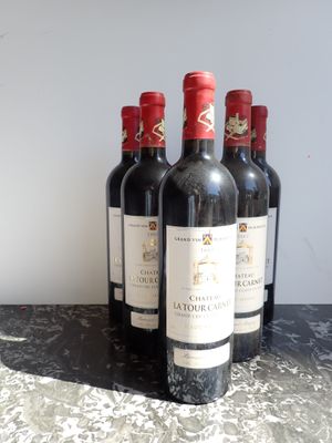 quatre bouteilles de vin rouge sont alignées sur une table