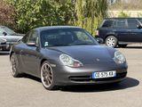 a grey porsche parked in a parking lot next to other cars