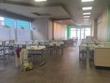 de nombreuses tables et chaises dans une grande pièce dont la porte est verte