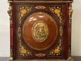 a small wooden cabinet with a gold medallion on it