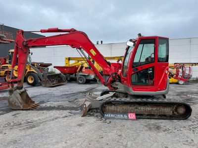 une pelleteuse rouge qui est à l'arrêt dans la terre