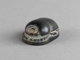 un gros plan d'une figurine représentant un escargot posée sur une surface grise