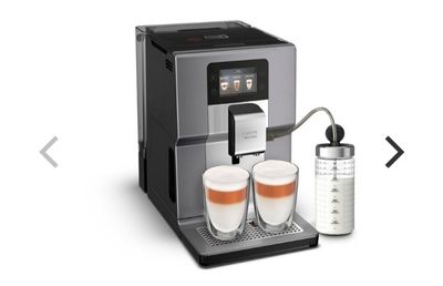 une machine à café argentée, avec deux tasses de café à côté