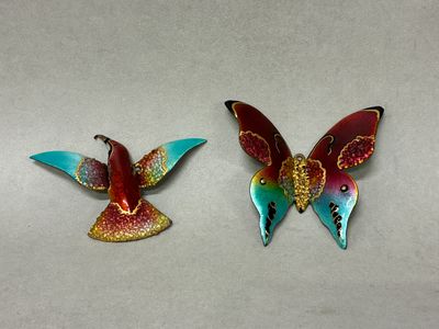 pair of colorful butterfly brooches on a white surface