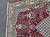 a red rug on the ground with a cat laying on it