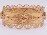 an image of a close up of a gold bracelet on a white surface