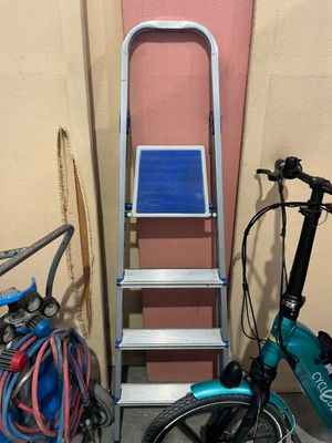 un vélo et une échelle près d'un mur rose