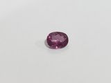 a pink sapphire stone on a white surface