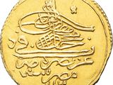a close up of a gold coin with arabic writing on it