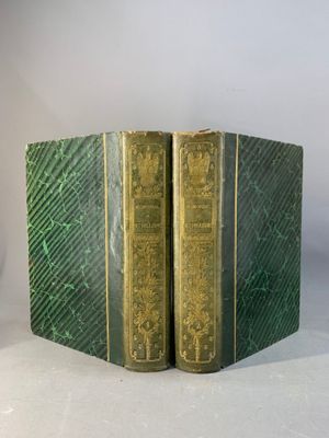 une paire de livres verts à la couverture dorée posés sur une surface blanche