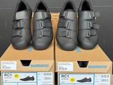trois paires de chaussures de route Shimano dans leurs boîtes, posées sur une table