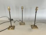 trois lampes de table en laiton avec des cordons noirs, sur fond blanc