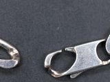 two pieces of silver metal are shown on a black surface