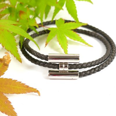 two black leather bracelets with silver clasps on a white surface