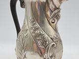 an antique silver coffee pot with a black handle on a stand