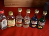several bottles of alcohol lined up on a red cloth