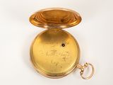 a gold pocket watch that has writing on it