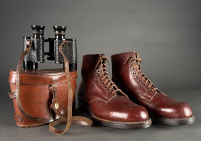 pair of red wing boots and a case with binoculars on a gray background