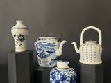 four blue and white vases and a teapot on a black table