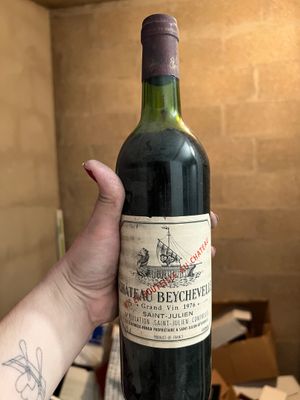 quelqu'un tient une bouteille de vin à la main dans une pièce remplie de cartons