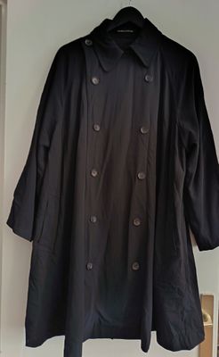 black trench coat hanging on a white wall in a room