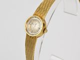 a close up of a gold wrist watch on a clear display