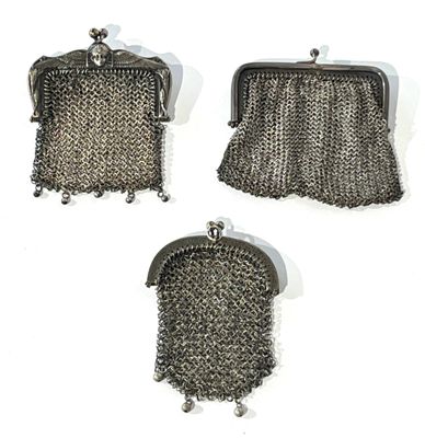 three metal purses with chains hanging from them on a white surface