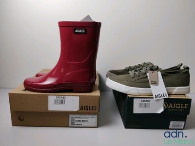 deux paires de bottes de pluie rouges et vertes posées sur des cartons