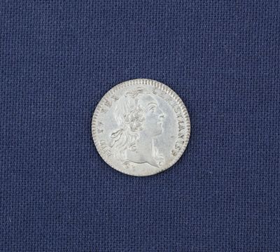 un gros plan d'une pièce d'argent posée sur un tissu bleu