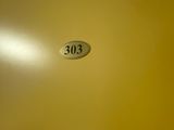 the door to the bathroom is painted yellow and has a small number on it