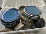 many plates and bowls in a plastic container on the counter