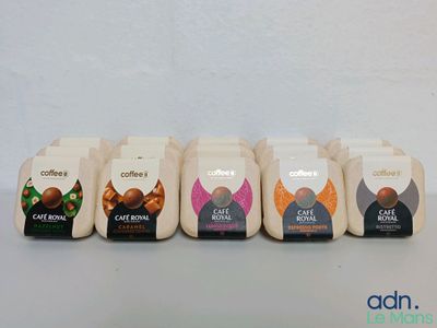 Quatre paquets de café sont alignés sur une table