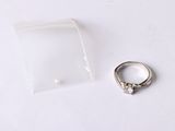 une bague en argent et un sac en plastique transparent posés sur une table