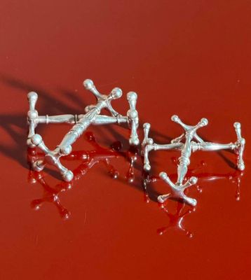 two pairs of silver earrings that are sitting on a red surface