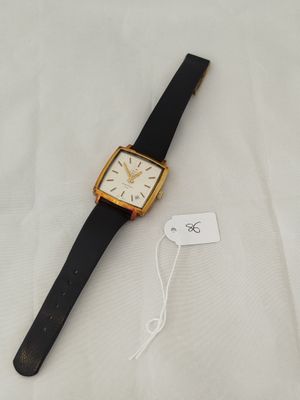 a close up of a watch on a white surface with a tag