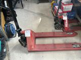 un chariot élévateur rouge dans un entrepôt, avec des cartons par terre