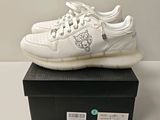 someone is wearing a white shoe with a lion on the side