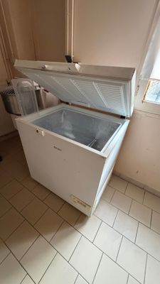 un congélateur coffre blanc posé dans une cuisine, près d'une fenêtre