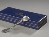 une cuillère en argent posée sur une boîte bleue