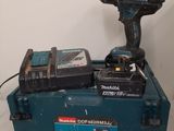 une perceuse sans fil et deux batteries posées sur une boîte à outils