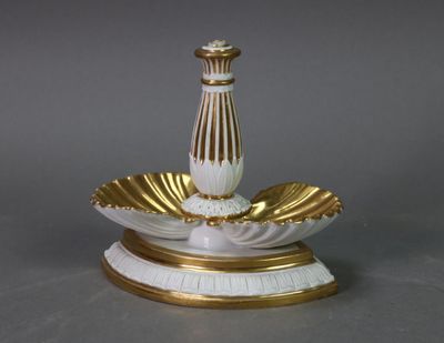 a white and gold vase on a stand on a table