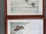 two paintings of birds are hanging on a wall above a toilet