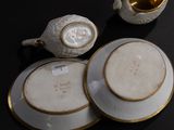 two cups and saucers on a table with a teapot