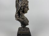 a bronze statue of a woman with a hat on her head