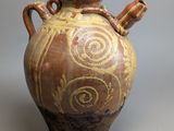 un vase marron et jaune posé sur une surface grise