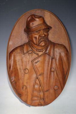 plaque en bois sculptée représentant un homme portant un chapeau et un manteau