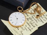 une montre de poche en or posée sur un morceau de papier