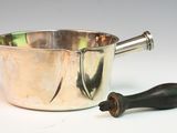 a silver pot with a wooden handle next to it